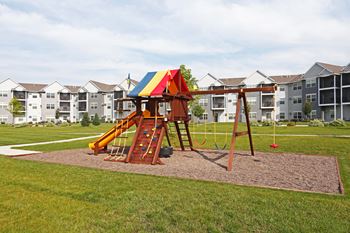 Outdoor playground surrounded by lush green grass.